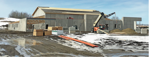 Pictured: Solid from the ground up: Llew Werner, Building Committee chair, advises that both the exterior school walls and the gym walls are constructed of precast concrete sections. In addition to having very good fire resistance and durability, the precast wall sections also have a substantial layer of high density foam insulation "sandwiched" in the middle of each section, which will result in a warm school. The gym walls were raised first and the gym roof trusses installed, and then the exterior walls and trusses will be installed. The roof will be sheeted and clad with metal roofing material.