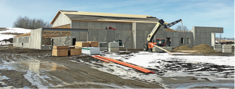 Pictured: Solid from the ground up: Llew Werner, Building Committee chair, advises that both the exterior school walls and the gym walls are constructed of precast concrete sections. In addition to having very good fire resistance and durability, the precast wall sections also have a substantial layer of high density foam insulation "sandwiched" in the middle of each section, which will result in a warm school. The gym walls were raised first and the gym roof trusses installed, and then the exterior walls and trusses will be installed. The roof will be sheeted and clad with metal roofing material. 